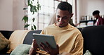 Funny, typing and man in home, tablet for social media and digital app for communication. Smile, laughing and person on sofa, connection and tech for online humor, happiness and message to contact