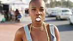 Face, city and black woman with chewing gum on vacation, travel and laugh on morning commute. Portrait, bald person and bubblegum in urban town for adventure, trip or funny tourist on holiday
