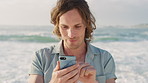 Happy man, phone and thinking with texting at beach for contact, typing and waves on summer vacation. Person, smartphone and smile with mobile app, notification or social media on holiday at seaside