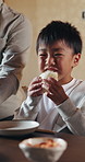 Boy, eating and food in dining room with family for feast, hunger or Japanese meal together. Bonding, dance and Hokkaido Milk Bread roll with excited child in apartment for traditional cuisine