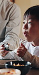 Boy, sushi and kid in home, family and eating together for nutrition, wellness and dinner table for protein. Tasty, child and seafood for healthy meal, hungry and Asian cuisine for lunch or rice