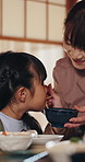Feeding, mother and girl with noodles in home for care, healthy food and nutrition for family bonding. Eating, Japanese woman and hungry child with chopsticks for lunch  in apartment, smile and love