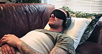 Blindfold, therapy and man with headphones on sofa, psychedelic appointment or soldier with eye mask. Mental health, counseling and person with military trauma on couch, audio and sensory deprivation