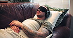 Blindfold, counseling and man with headphones on sofa, psychedelic session or soldier with eye mask. Mental health, therapy and person with military trauma on couch, audio and sensory deprivation