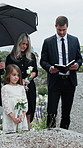 Family, tombstone and gathering with holy bible at funeral for grief or condolences in cemetery. Group, people or priest with book of god for christian burial, memorial service or death in graveyard