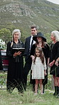 Funeral, family and reading bible at cemetery for burial, memorial service or farewell ceremony. People, religion and officiant with book at graveyard for grief, death and faith with generations