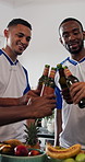 Men, friends and toast with beer in home for celebration, reunion or party with football shirt for game. People, group and drinks with beverage, alcohol and bonding for sports tournament at apartment