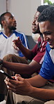 Friends, phone and watching tv in house with football match, social media distraction and men bonding. Happy people,  text message and broadcast in lounge with soccer game, chill and eating popcorn.