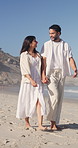 Couple, walking and holding hands on beach with summer holiday, conversation and bonding together. Happy, married people and outdoor by ocean with love, tropical vacation and discussion for travel.