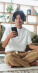 Man, headphones and browsing in home with yoga mat, text message or wellness break for streaming music. Asian person, smile and scroll on floor with fitness app, holistic health and tech for audio.