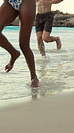 People, legs or running with water splash on beach for fun summer, holiday or weekend together. Group, friends or playing on ocean coast for playful bonding, vacation trip or outdoor travel in nature