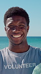 Face, black man and volunteer with plastic bag at beach for clean up, waste management and stop pollution. Portrait, male person and happy for recycling dirt, social responsibility and cleaning shore