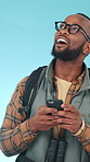 Hiking, smile and black man in studio with phone, wow face or typing social media post for adventure. Happy, person and wonder with scenic view, tech and text message for trekking on blue background.