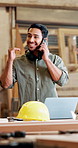 Phone call, happy and carpenter with laptop in workshop for delivery information with furniture for repairs. Cellphone, computer and male woodworker on mobile discussion for timber business in office