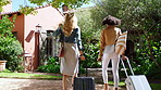 Friends, luggage and enter lodge outdoor for holiday destination, weekend getaway and sightseeing. Back, happy women and villa arrival with suitcase for vacation trip, scenery and countryside travel