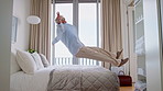 Travel, man and jump on bed at hotel for relax, vacation and tired with comfort on mattress. Mature person, holiday and resting in bedroom of motel for break, peace and calm with hospitality on trip