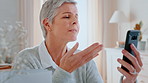 Phone, video call and old woman blow kiss in house, virtual contact and wave for digital communication. Goodbye, connection and senior person with app for conversation, mobile and talking online