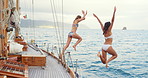 Friends, yacht and women jump in ocean for summer holiday, vacation and tropical adventure. Travel, tourism and people in sea for swimming, freedom and fun on luxury cruise, trip and explore island