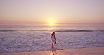 Woman, sunset and travel with walking in ocean, calm and vacation wellness outdoor. Sky, space and female person with splash on shore for peace, fresh air and break on getaway trip for self care