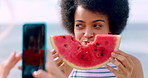 Outdoor, eating and or woman with watermelon for picture, social media post or friends holiday memory. Summer vacation, phone and happy people with photography by beach, fruit or weekend break update