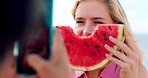 Outdoor, woman and watermelon smile for photography, social media post or friends holiday memory. Summer vacation, phone and happy people with playful picture by beach, fruit or weekend break update