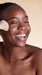 Happy, woman and makeup application with brush, foundation and facial product for beauty routine. Black person, laugh and cosmetic tools for self care, glowing skin and grooming on studio background.