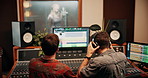Production, discussion and producers with headphones for music in studio working on album or song. DJ, equipment and male sound technicians with computer for mixing audio track in recording booth.