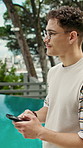 Thinking, serious and man with phone at resort for travel, social media and browsing website. Person, outdoor and mobile with reflection, online itinerary and notification update on holiday at hotel