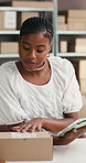 Box, label and tablet with black woman in logistics office for delivery management or tracking. App, reading and supply chain with African employee in workplace for distribution or shipping report