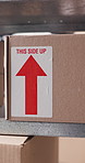 Label, arrow and stock with box on shelf in storage depot for delivery, distribution or shipping. Cardboard, package or parcel in empty warehouse for ecommerce, logistics and supply chain export