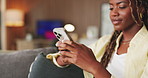 Smile, message and black woman with phone on sofa for dating app, platform and digital conversation. Person, happy and typing with tech in home for profile match, response and online communication