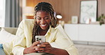 Laugh, text and black woman on sofa with phone, online communication and comic post on social media. Happy, digital and person in house with tech, funny message or meme reaction on chat app.