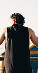 Fitness, headphones and back of man in city for exercise, workout and rest after training. Thinking, outdoor and person with music, podcast and radio for challenge, endurance and break for wellness