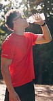 Man, fitness and drinking with water in nature for hydration, workout break or outdoor recovery. Active, male person or beverage with bottle or mineral liquid for exercise, rest or training in forest