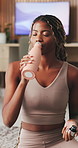 Yoga, woman and drinking water in house with phone, wellness and natural detox for holistic health. Thirsty, black person and exercise recovery in home with tech, bottle and beverage for hydration.