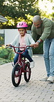 Learning, father and girl with bicycle in backyard, support and guidance for coordination development. Smile, teaching balance and man with child for cycling practice, improve motor skills or bonding