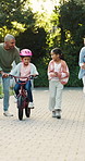 Family, applause and girl with bicycle in backyard, support and guidance for coordination development. Smile, cycling or people with children for balance practice, outdoor or clapping for achievement