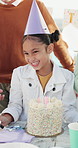 Family, singing and child with cake at birthday party for celebration, special day and cheering outdoor. Happy, parents and girl with dessert, hat and candles for event, gathering and milestone
