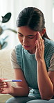 Upset, pregnancy test and woman on sofa in home with regret, stress or mistake for unplanned maternity. Anxiety, scared and female person with positive result for failed birth control in house.