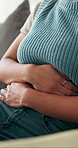 Stomach pain, sofa and woman in home with indigestion, constipation or endometriosis symptoms. Belly ache, sick and female person with abdominal cramps for ibs, menstruation or diarrhea in house.