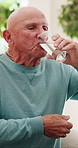 Senior, man or drinking with water in home for hydration, medication or healthy vitamins. Elderly, male person or thirsty pensioner with mineral liquid or beverage for nutrition or digestion in house