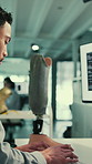 Lab, computer and man with artificial limb for research, innovation and design for medical science. Typing, technician and worker with prosthetic software for sensory model or neural integration