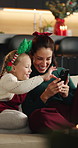 Christmas, mother and child in home with phone, bonding together and surprise for online gaming win. Festive season, woman and daughter smile on sofa with tech, mobile app and shock for game winner.