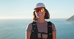 Happy, hiking and face of woman in nature by ocean for discovery, adventure or exercise on holiday. Smile, sunglasses and portrait of female person outdoor for trekking by sea for active on vacation.