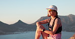 Woman, hiking and thinking with sunglasses on mountain with ocean view, space and relax on summit. Girl, outdoor and break on peak, rocks and perspective with trekking, adventure and smile in summer