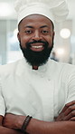 Happy, black man and face of chef in restaurant with confidence for career in hospitality. Crossed arms, kitchen and portrait of African culinary expert with customer service in catering at hotel.