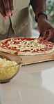 Person, hands or pizza with cheese on table for meal prep, ingredients or topping to recipe in home. Culinary, art or sprinkle with cheddar on pastry dish for italian cuisine, lunch or hospitality
