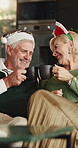 Christmas, cheers and couple in home, funny and tradition with eggnog, celebration and love. Cacao, mature man or woman on sofa, Xmas holiday or bonding together with humor, talking or festive season