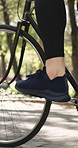 Cycling, feet and fitness with woman outdoor for cardio training, riding bike or workout routine. Bicycle, exercise and legs of female cyclist in park for challenge, performance or physical activity