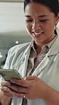 Happy, asian woman and typing with phone in office for social media, communication or network. Female person, employee or texting with smile on mobile smartphone or app for conversation in workplace
